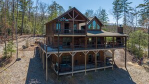 Eine zweistöckige Blockhütte mit Balkon, umgeben von Bäumen.