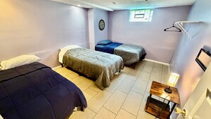 Habitación con dos camas individuales, un ventanal pequeño, un dardo y una lámpara.