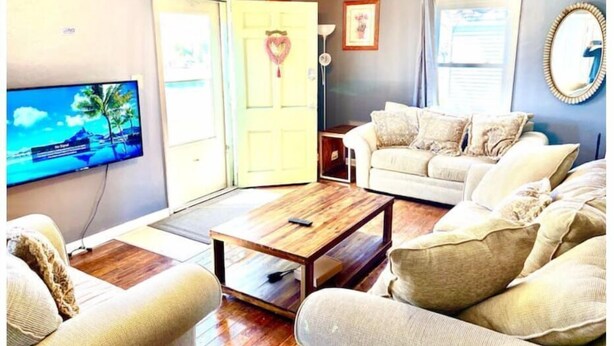 Una sala de estar con televisor, sofá, mesa de centro y una puerta.