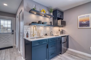 A modern kitchen with blue cabinets, white countertops, and a stainless steel sink.
