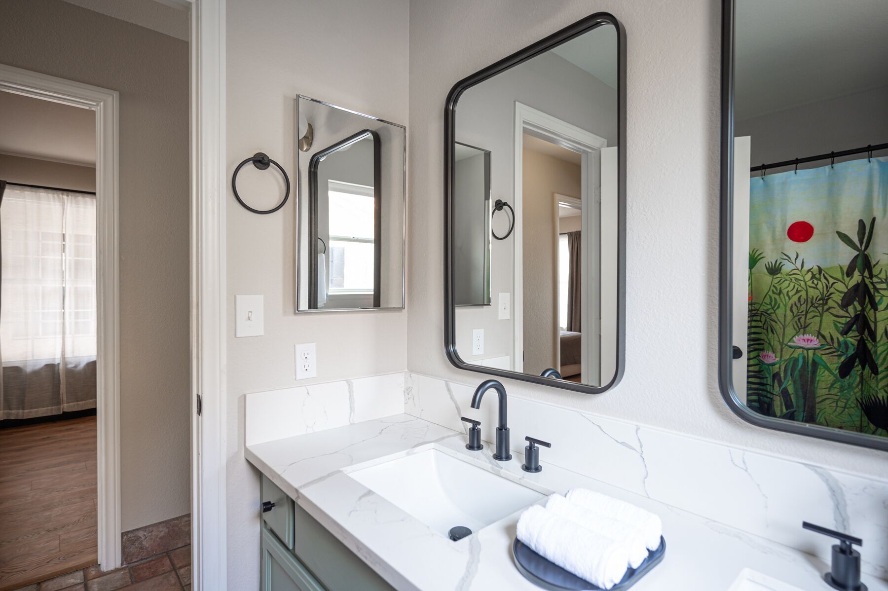 A bathroom with a white marble sink, two mirrors, and a towel on the counter.