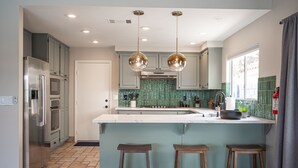 A modern kitchen with a large island, stainless steel appliances, and a green backsplash. - Casa Leon: 4BR House w/ Pool near Strip! (Las Vegas)