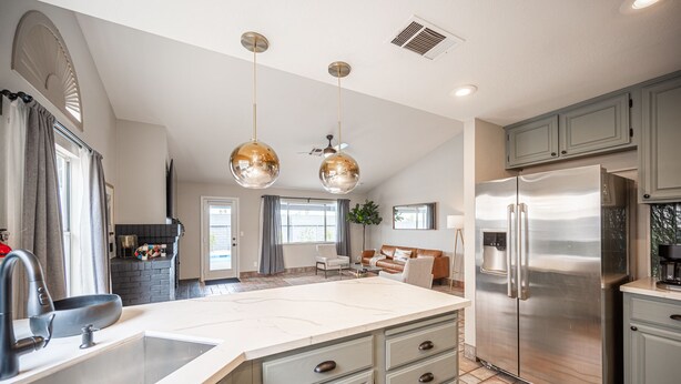 A spacious kitchen with a large island, stainless steel appliances, and a modern pendant light fixture. - Casa Leon: 4BR House w/ Pool near Strip! (Las Vegas)