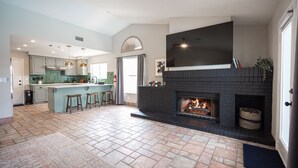 A spacious living area with a fireplace, a kitchen with a large island, and a dining area. - Casa Leon: 4BR House w/ Pool near Strip! (Las Vegas)