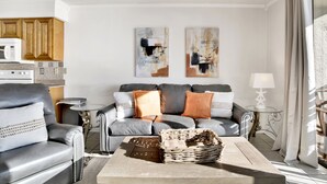 A modern living room with a grey sofa, a coffee table, and a kitchen area in the background. - Beachfront @ Seaside Beach & Racquet 1BR • Sleeps 4 • Amazing Views (Orange Beach)