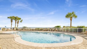 A swimming pool with a tiled deck, palm trees, and a view of the ocean. - Beachfront @ Seaside Beach & Racquet 1BR • Sleeps 4 • Amazing Views (Orange Beach)