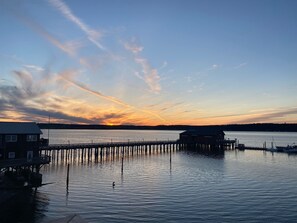 A waterfront property with a dock extending into calm water, surrounded by a forested landscape.