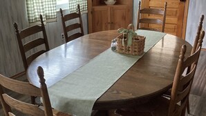 A dining room with a wooden table, six chairs, a cabinet, and checkered curtains. - Farmhouse - in the country but close to everything. 4 bedrooms-Sleeps 10 (Independence)