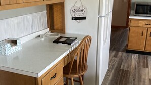 A kitchen with wooden cabinets, a white countertop, a wooden chair, and a white refrigerator. - Farmhouse - in the country but close to everything. 4 bedrooms-Sleeps 10 (Independence)