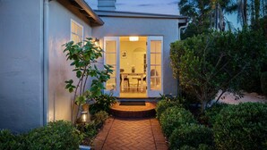 A house with a well-lit entrance, a paved pathway, and a garden area.