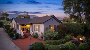 A two-story house with a porch, a small garden, and a fire pit.