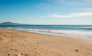 Enjoy a serene beach experience with a wide stretch of sand and breathtaking views of the surrounding mountains and sea.