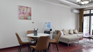 A modern living room with a round dining table, two chairs, a sofa, and a water dispenser.