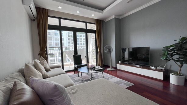 A modern living room with a sofa, a coffee table, a TV, and a potted plant.