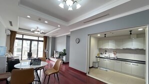 A modern hotel room with a dining area, a kitchen, and a large window with curtains.