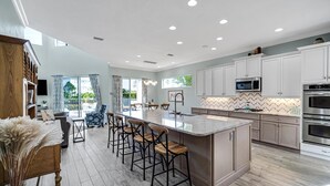 Una cocina moderna con una isla grande, taburetes de bar y una zona de comedor con vistas.