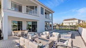 Una casa de dos pisos con un patio que incluye mobiliario exterior y una piscina.