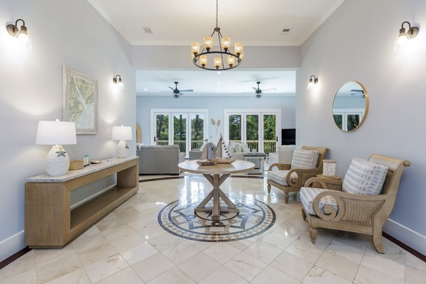 Elegant coastal-inspired living space with soft blue walls, natural wood accents, and bright natural light streaming through large glass doors.
