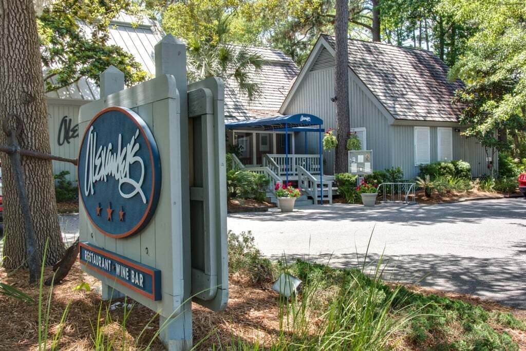 A restaurant and wine bar sign with a covered outdoor seating area and a building in the background.