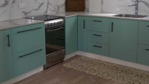 A kitchen with teal cabinets, a stainless steel sink, and a marble backsplash. - TonLin Pewee Drive 1 Bedroom (Gros Islet)