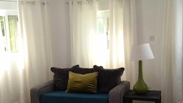 A living room with a sofa, a lamp, and a rug. - TonLin Pewee Drive 1 Bedroom (Gros Islet)