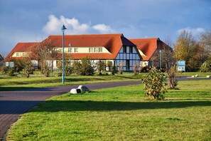 Ein traditionelles Gebäude mit rotem Ziegeldach, einer symmetrischen Fassade und einem gepflasterten Weg zum Eingang.