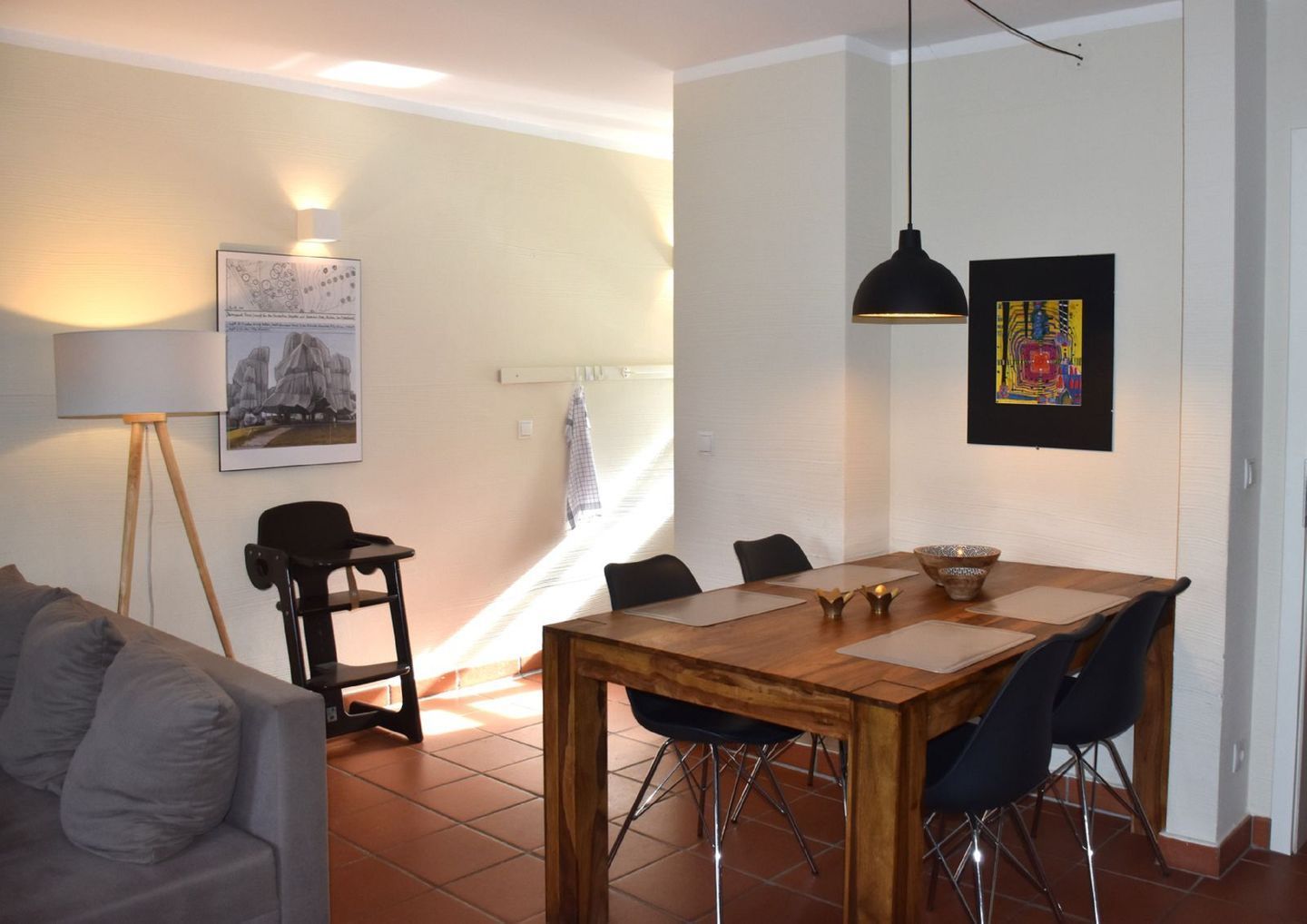 Un coin repas avec une table en bois, des chaises et une suspension.