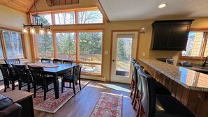 A spacious kitchen with a large island, wooden cabinetry, and a view of the outdoors through large windows. - MWP25 Updated 3 bed 3 bath condo with mountain ski slope views in Bretton Woods (Bretton Woods)