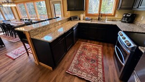 A kitchen with dark cabinets, granite countertops, a central island, and a large window. - MWP25 Updated 3 bed 3 bath condo with mountain ski slope views in Bretton Woods (Bretton Woods)
