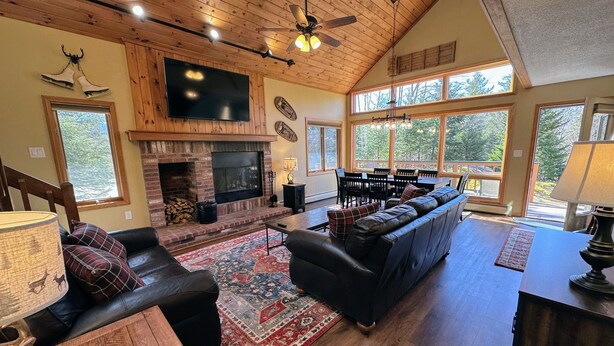 A spacious living room with a fireplace, leather sofa, and a large TV. - MWP25 Updated 3 bed 3 bath condo with mountain ski slope views in Bretton Woods (Bretton Woods)