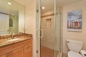 Ein Badezimmer mit Granitwaschtisch, Duschkabine aus Glas und Toilette.