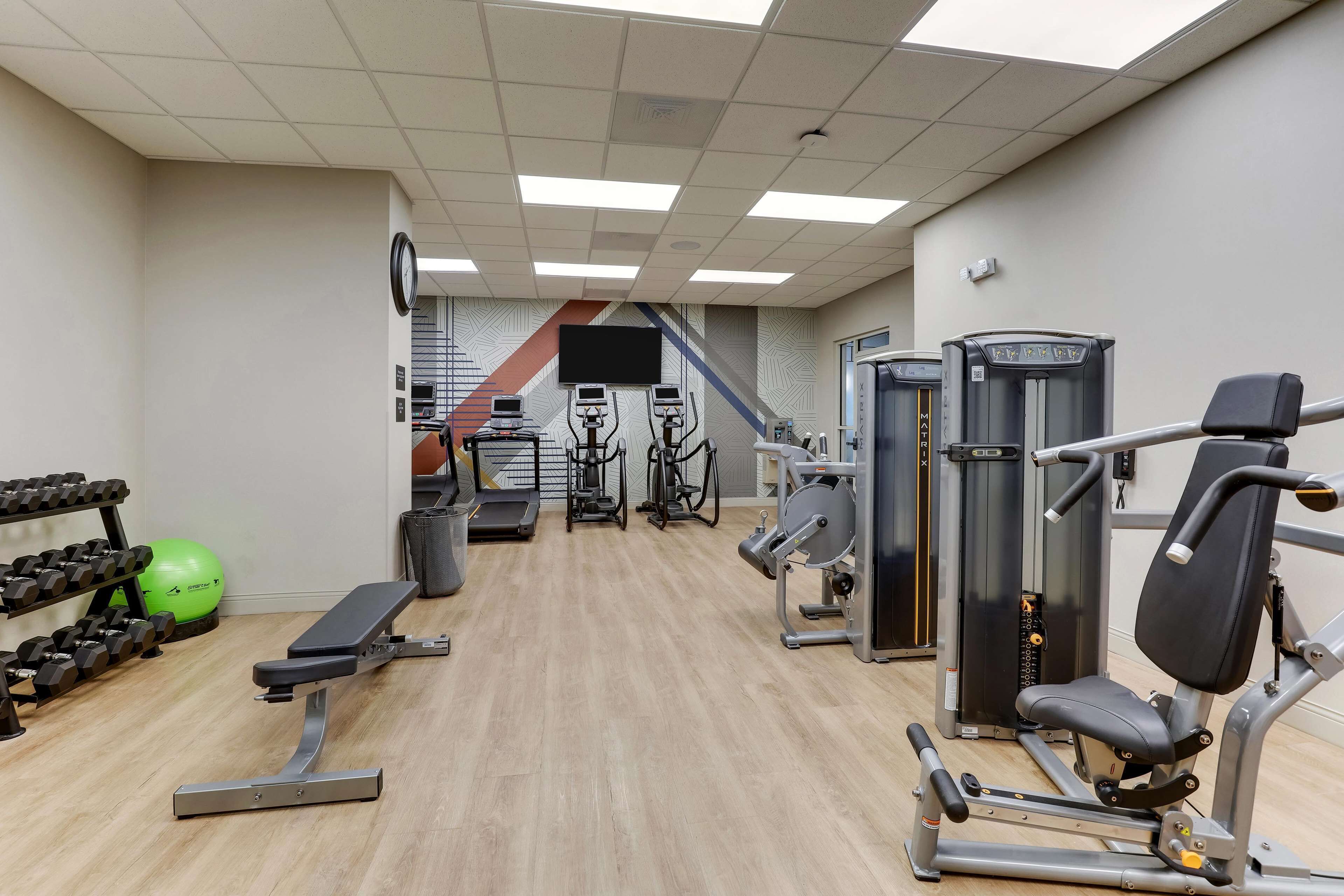 A gym with cardio equipment, weight machines, and dumbbells.