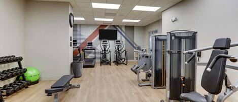 A gym with cardio equipment, weight machines, and dumbbells.