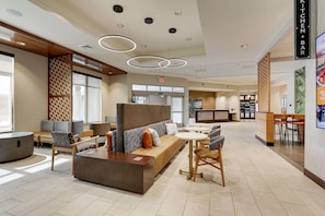 A modern hotel lobby with a reception desk, seating area, and a bar. - Drury Plaza Hotel Tallahassee (Tallahassee)