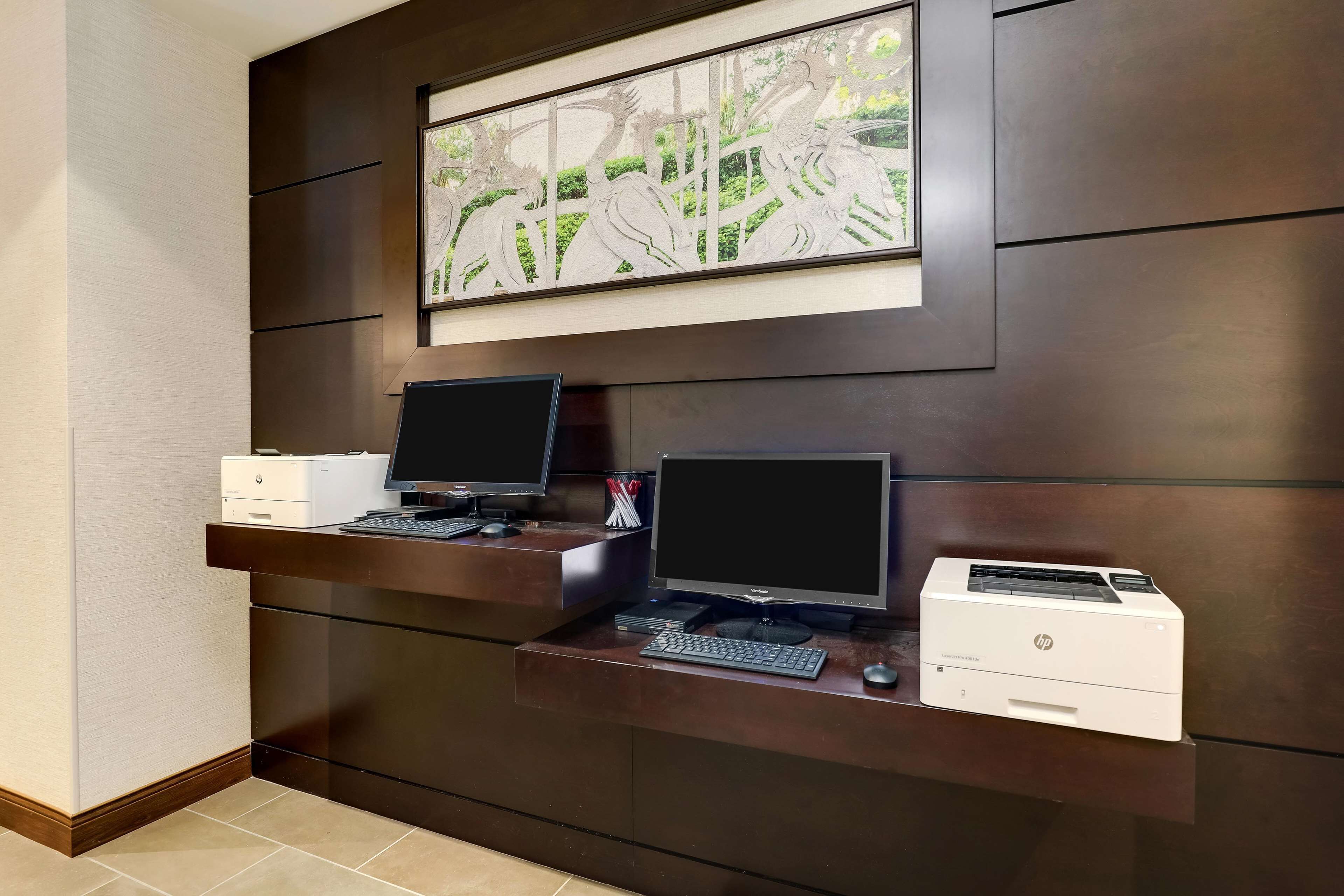 A reception desk with two monitors, a printer, and a framed artwork above.