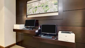 A reception desk with two monitors, a printer, and a framed artwork above.