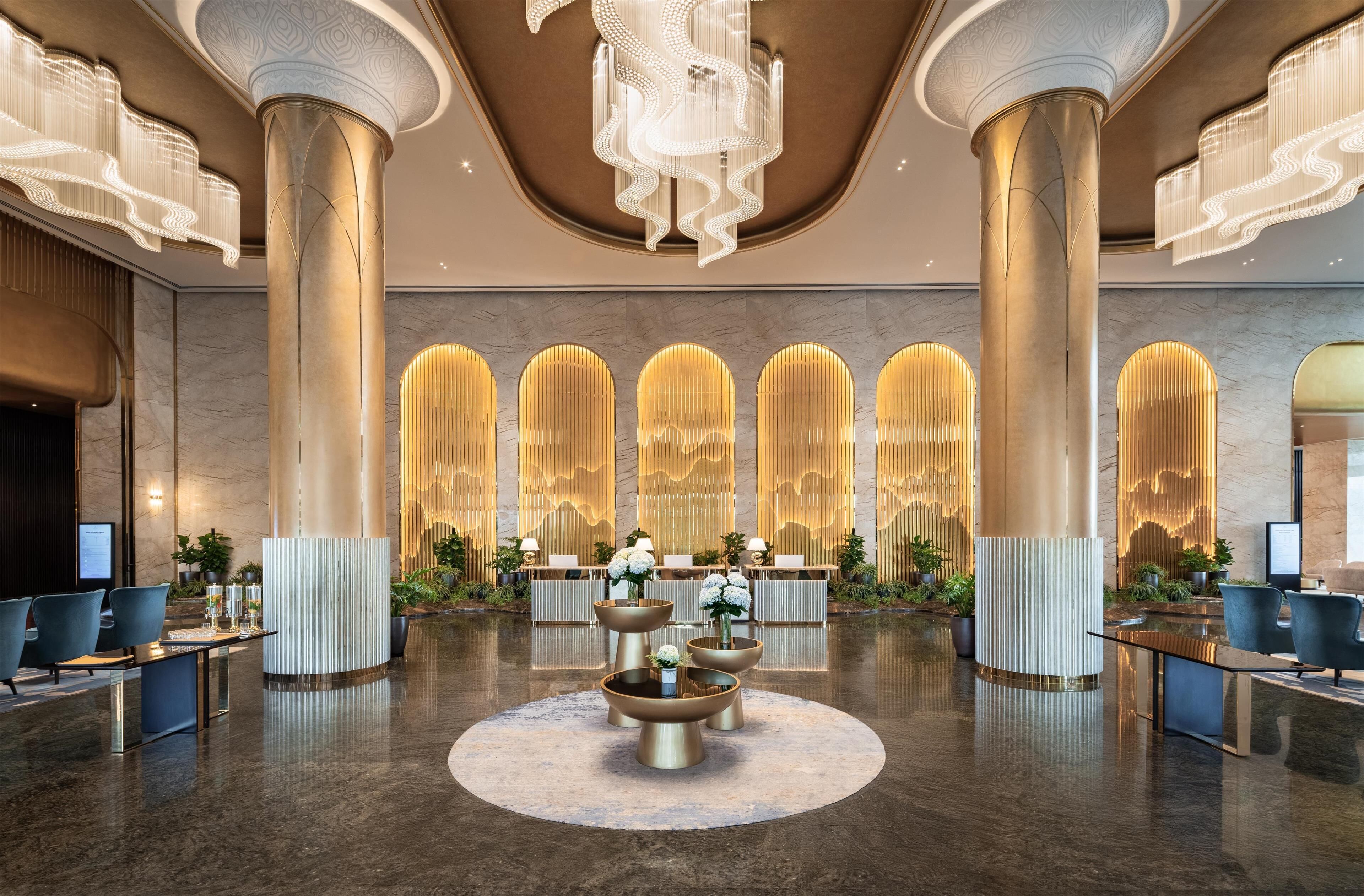 A spacious lobby with high ceilings, large columns, and a central seating area with a round table.