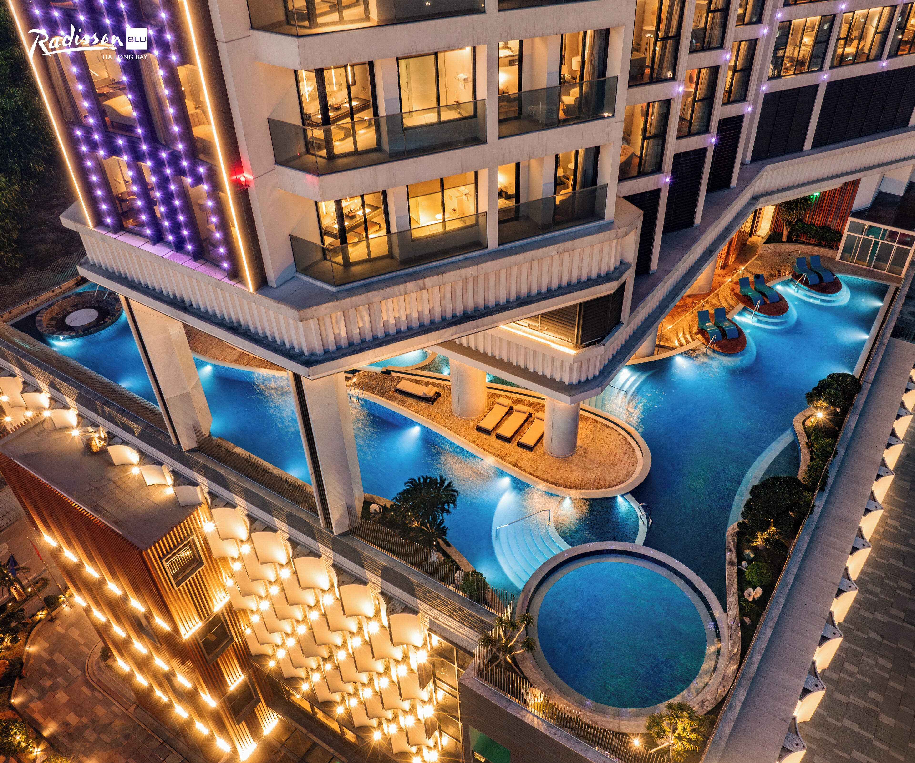 Un hotel de varios pisos con zona de piscina que incluye tumbonas y un jacuzzi.
