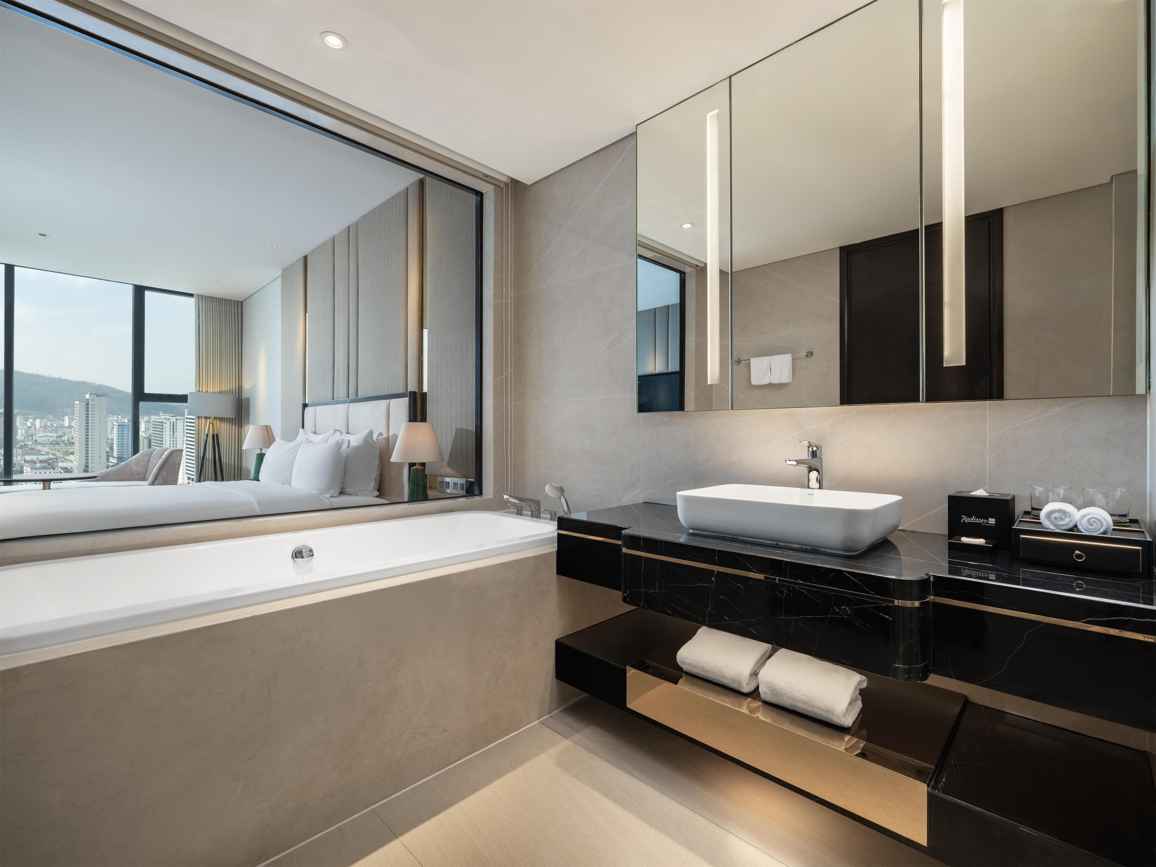 A modern bathroom with a large bathtub, a sink, and a mirror.