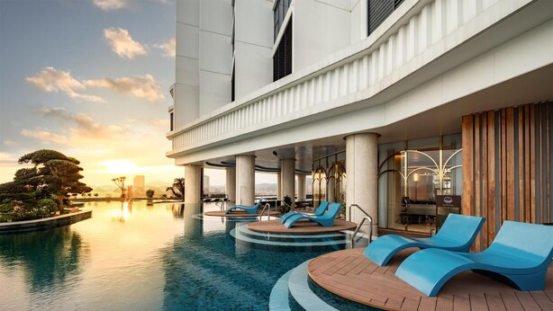 A modern hotel pool area with tiered seating and a view of the sunset. - Radisson Blu Hotel, Ha Long Bay (Bai Chay)
