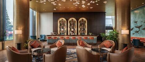 A lobby with a bar area, seating with cushions, and a patterned carpet.