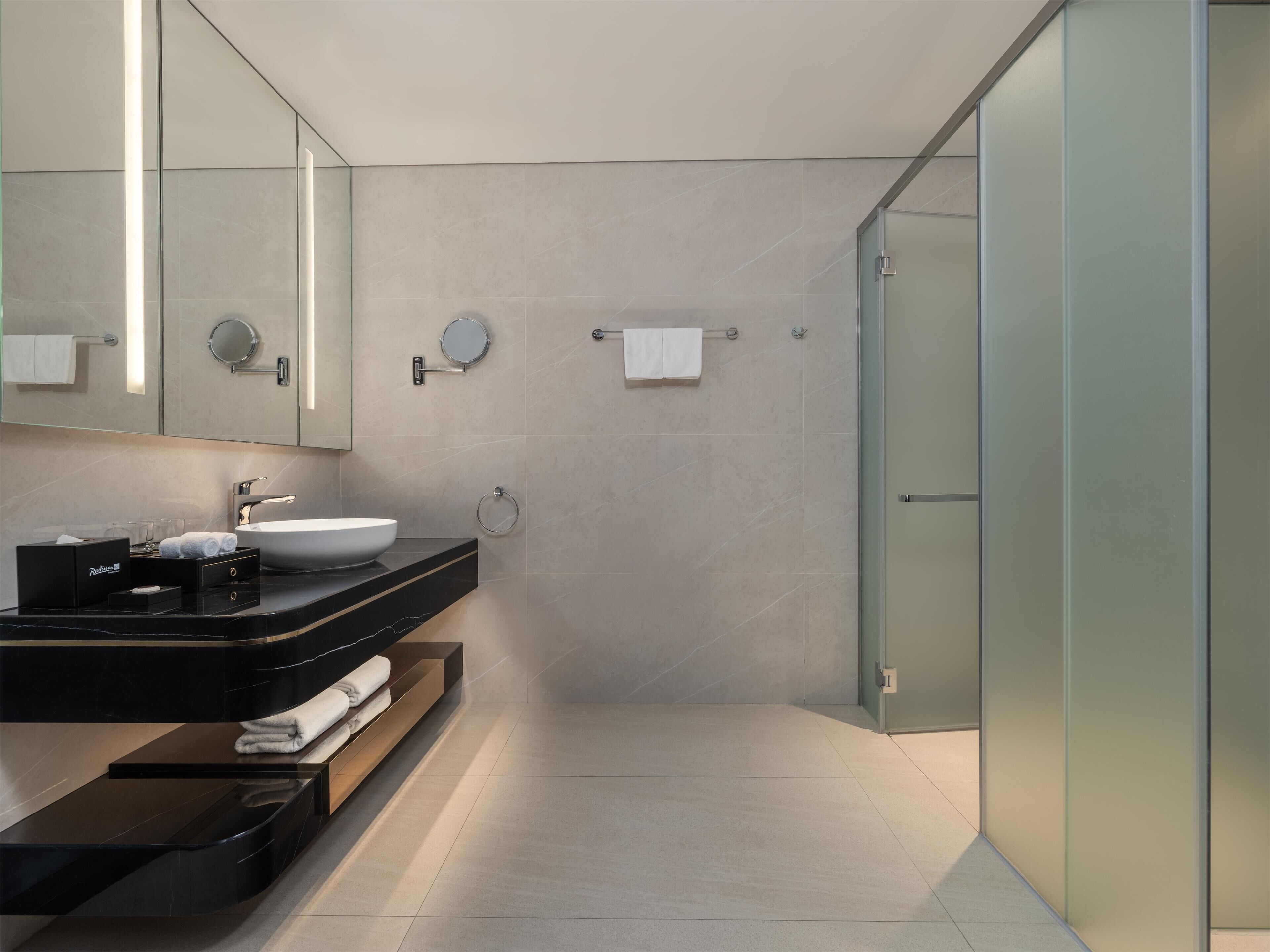 Une salle de bain moderne avec un meuble-lavabo noir, un grand miroir et une cabine de douche en verre.