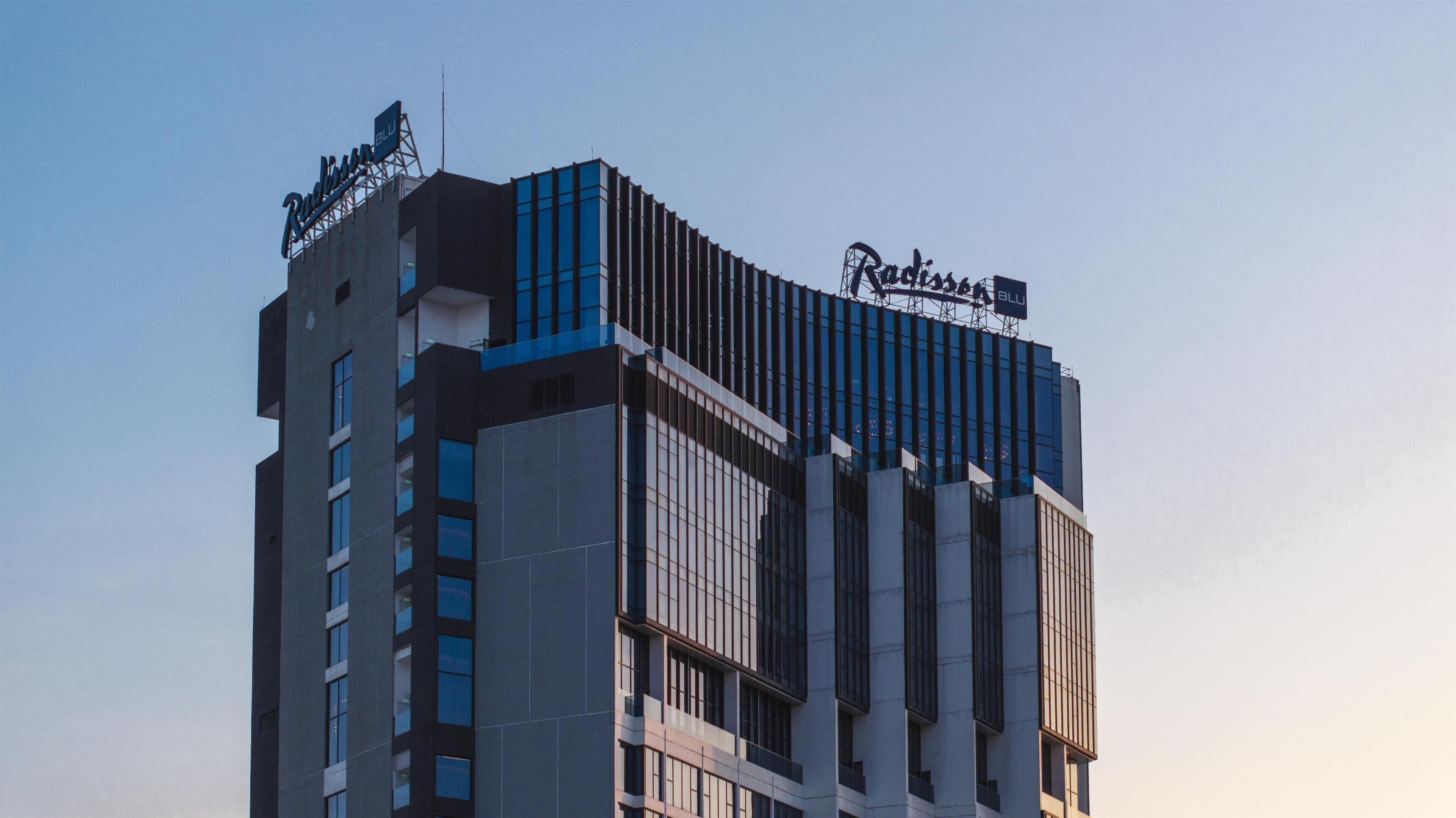 A modern hotel building with a prominent sign reading "Radisson Blu" at the top.