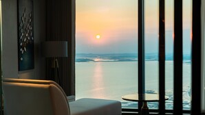 A modern hotel room with a large window offering a view of the sea at sunset. - Radisson Blu Hotel, Ha Long Bay (Bai Chay)