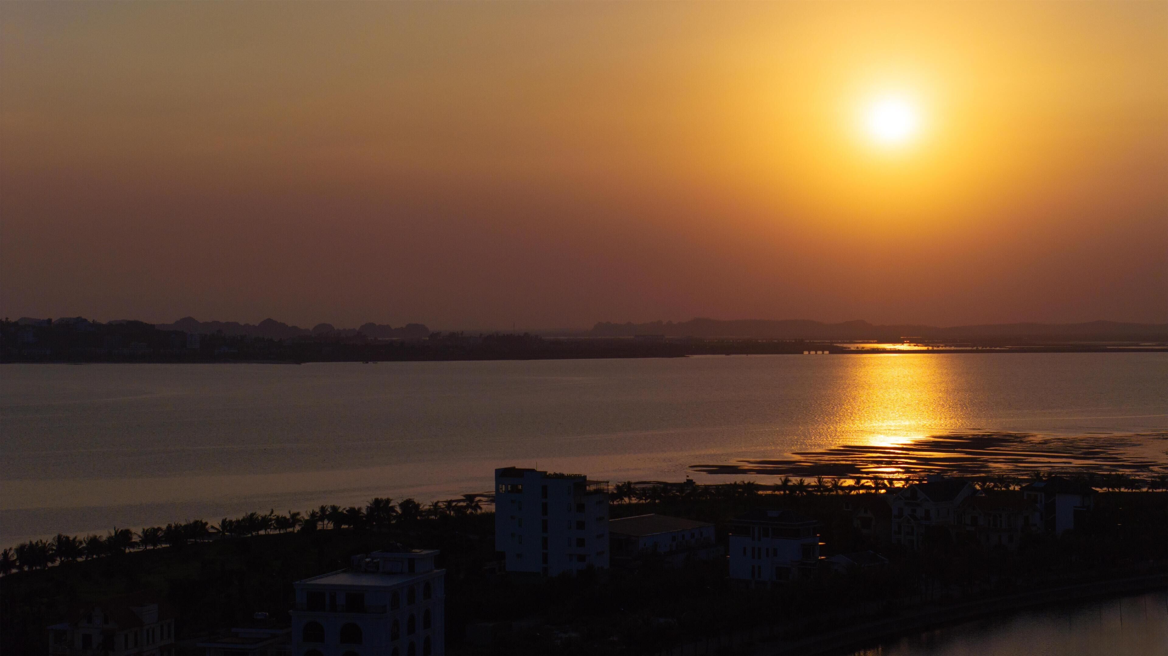 A sunset over a body of water with buildings in the foreground.