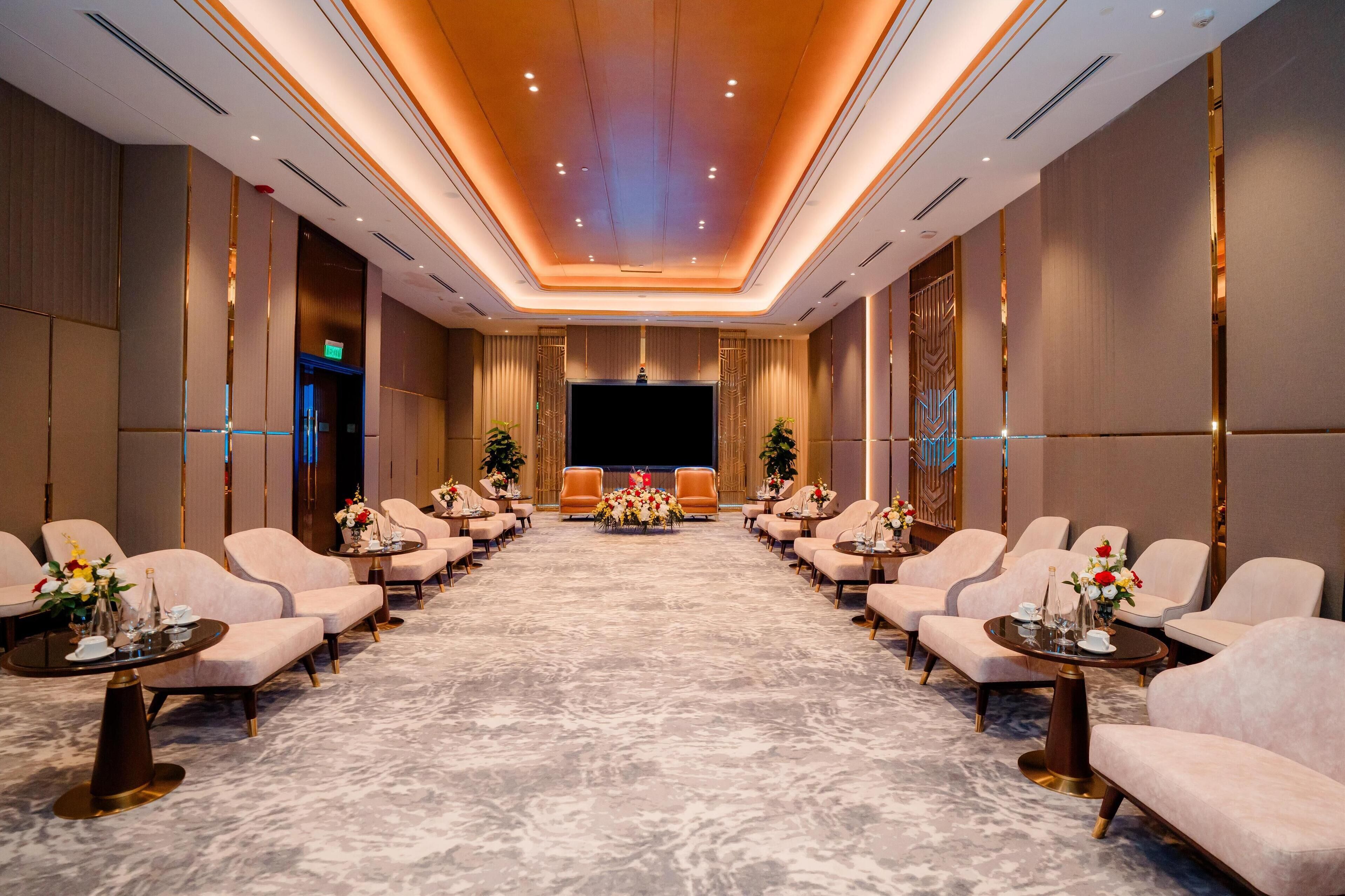 A conference room with a long table, multiple chairs, and a large screen.