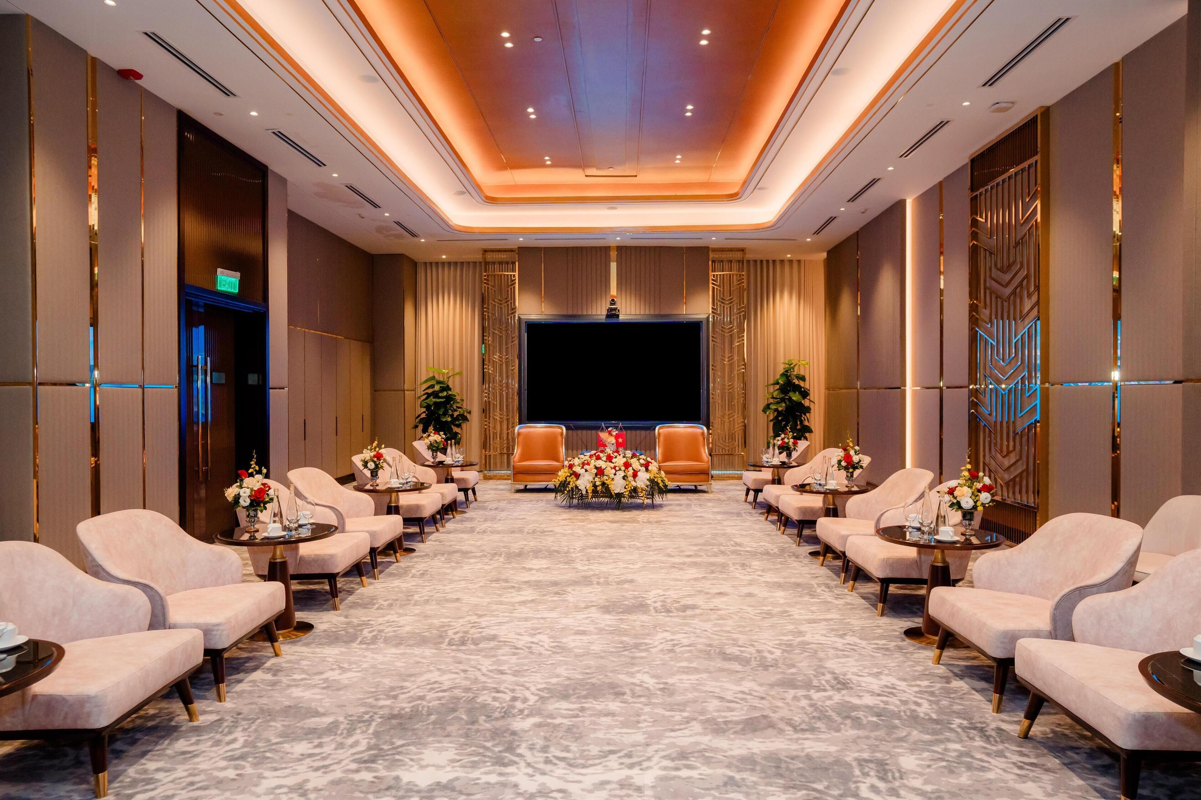 A conference room with a long table, chairs, and a stage.