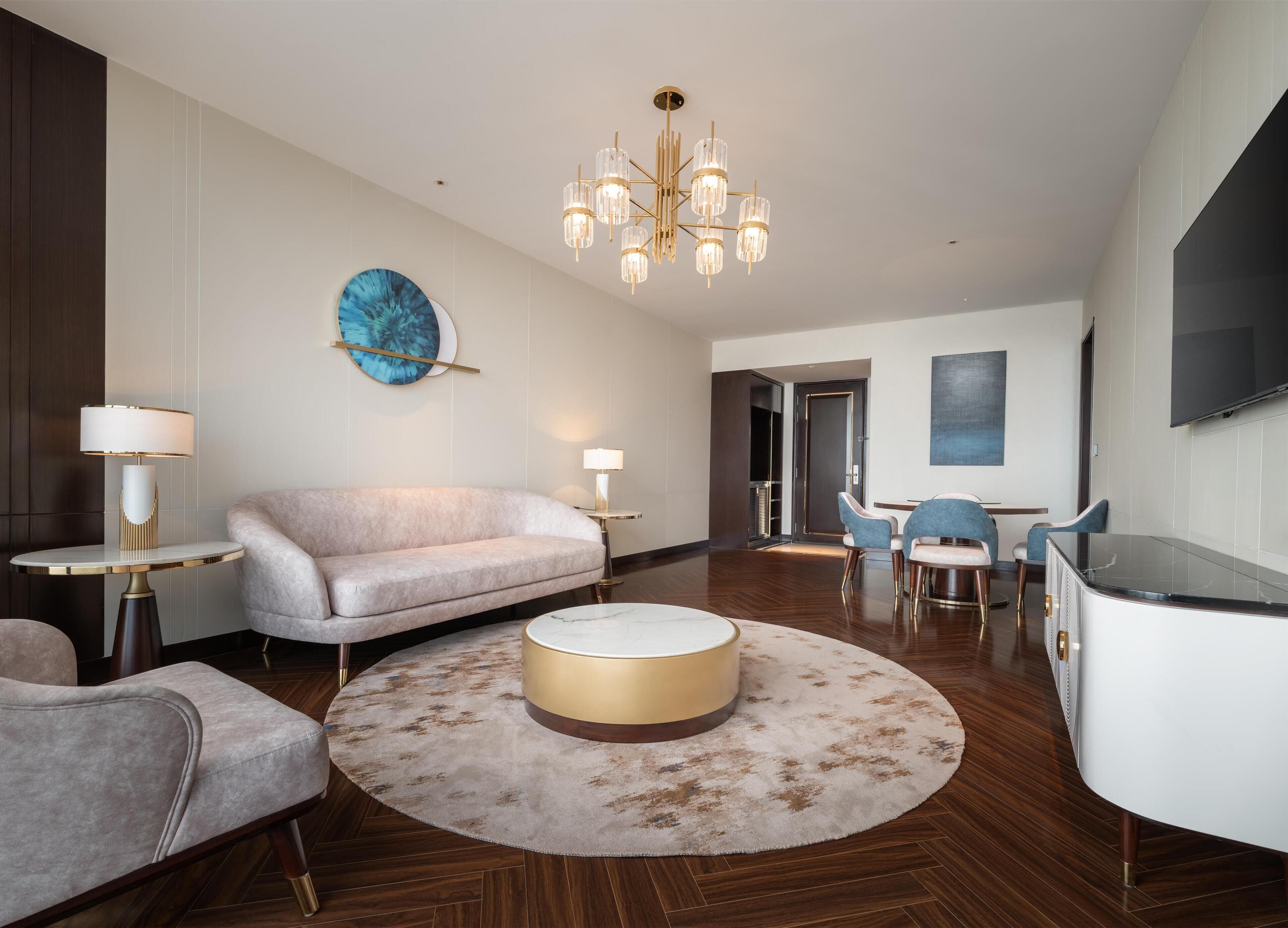 Ein modernes Wohnzimmer mit einer Couch, Sesseln, einem Couchtisch und einer Pendelleuchte.