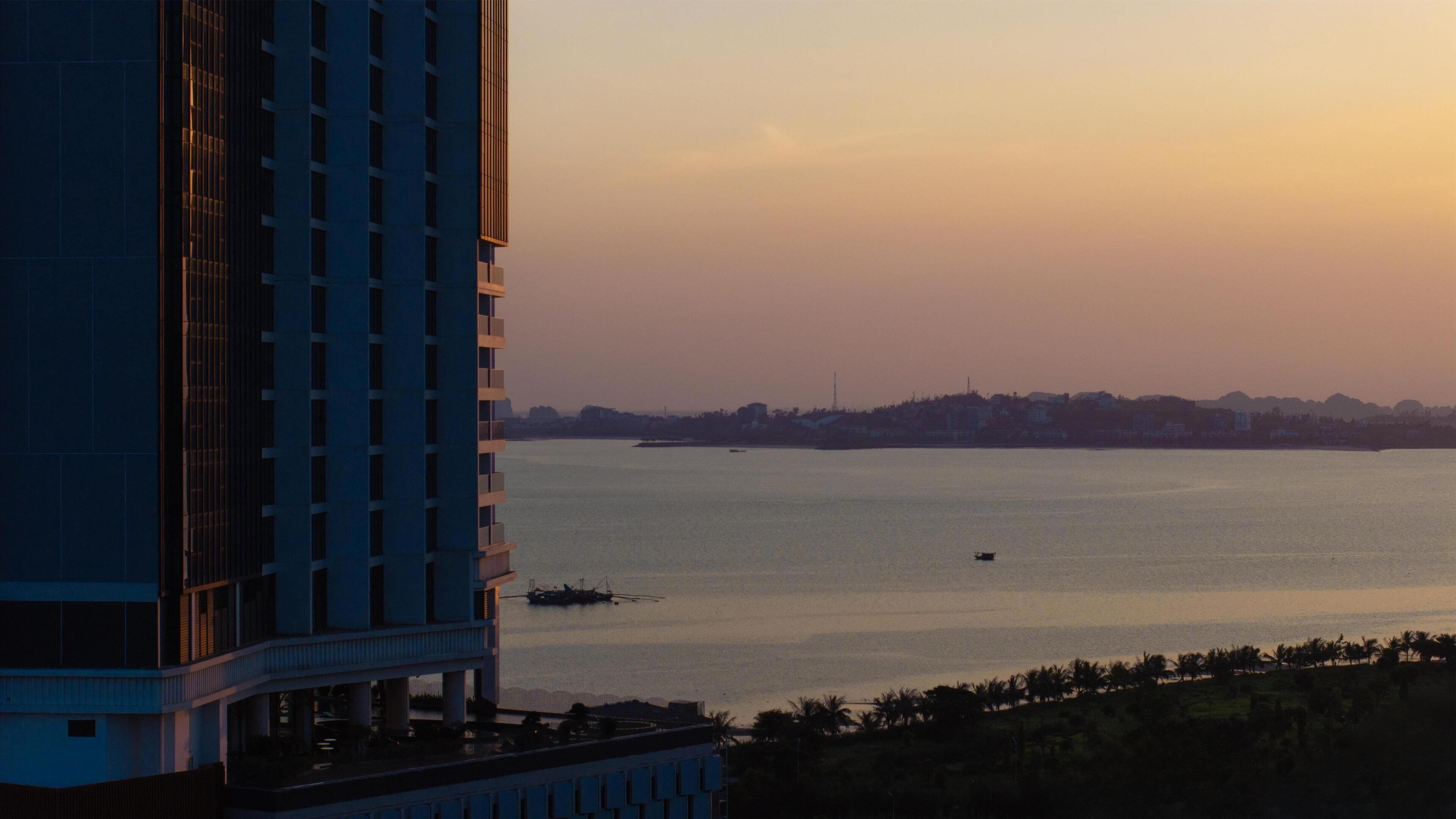Un immeuble de grande hauteur offrant une vue sur une étendue d’eau calme et une côte lointaine.