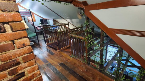 Un escalier en bois, avec un mur de briques d’un côté et un panneau blanc de l’autre.